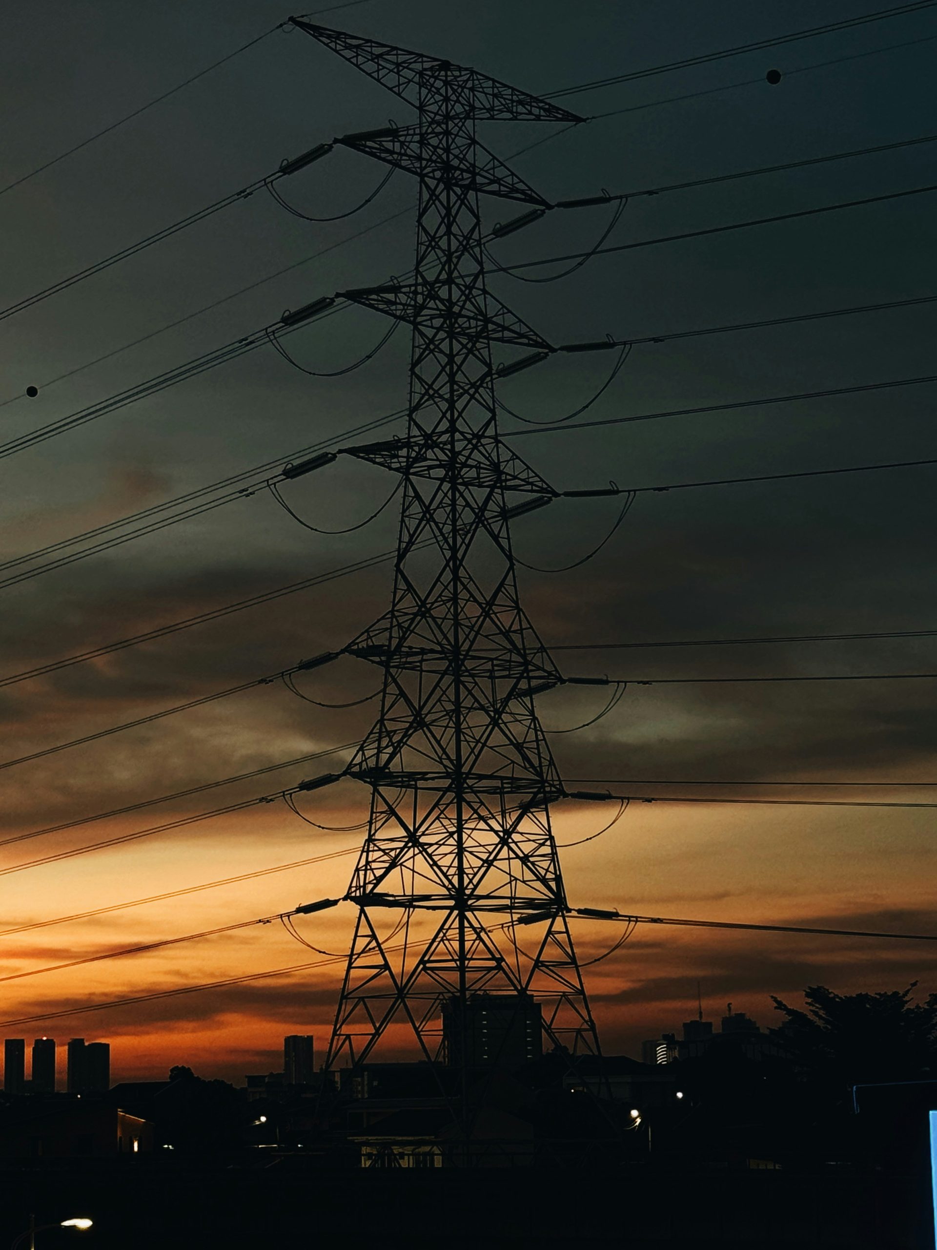 Silhouette eines Strommasts vor einem dramatischen Sonnenuntergangshimmel.