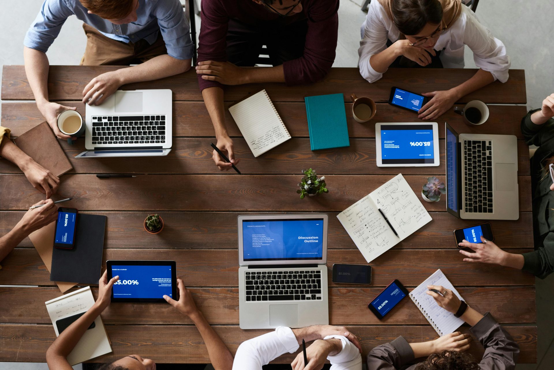 Luftaufnahme eines vielfältigen Teams in einer Geschäftsbesprechung, das Laptops und Tablets verwendet.