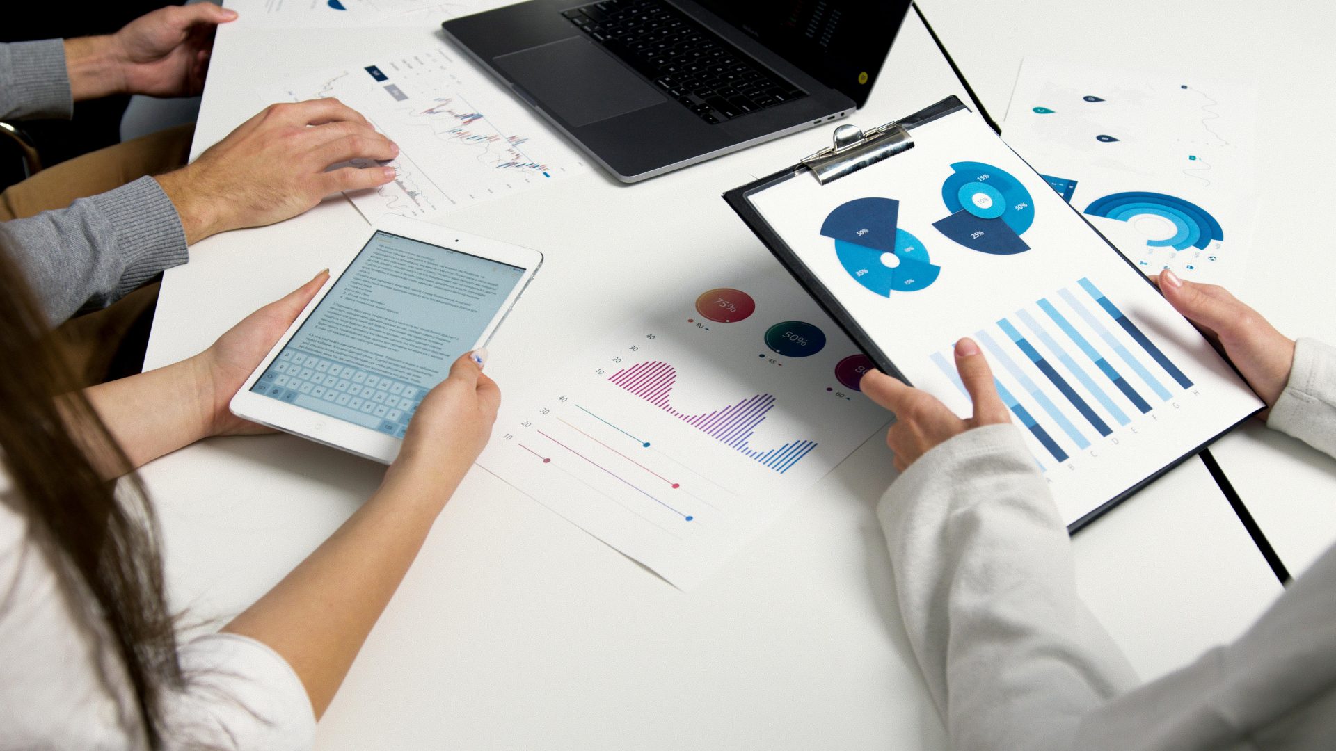 Ein Team analysiert Finanzdiagramme und digitale Berichte während einer Geschäftssitzung.